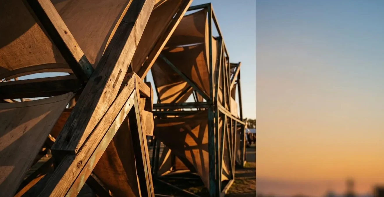 Installation scénographique révélée par la lumière dorée rasante du coucher de soleil, créant des jeux d'ombres et de textures sur une structure artistique