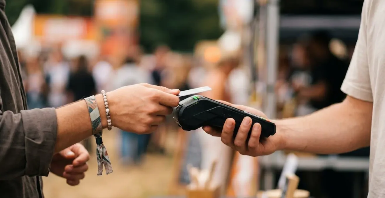 Gros plan sur une interaction de paiement sans contact avec bracelet NFC lors d'un achat en festival