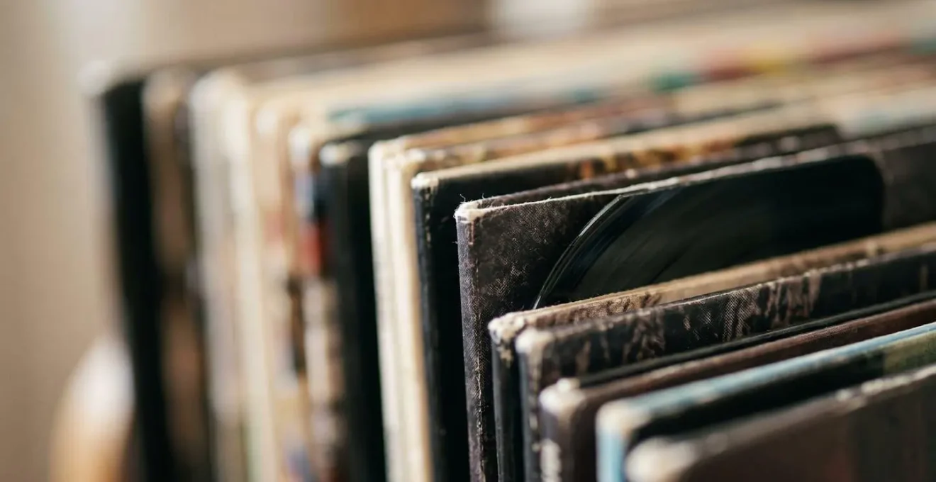Gros plan macro sur la tranche texturée de vinyles rangés verticalement, révélant les détails matériels et tactiles du support physique